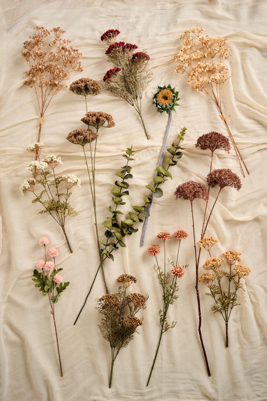 Konstblommor från Ib Laursens höstkollektion i cremefärgade, bruna, rosa och gyllene nyanser på ljust tyg.