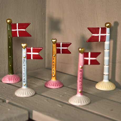 Keramikflaggor från Speedtsberg, både med och utan text på flaggstången, står på en hylla