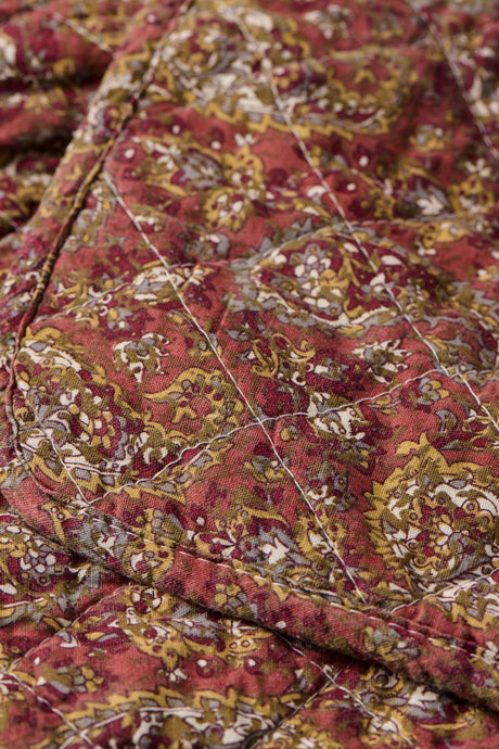 Närbild av quilt från Ib Laursen med detaljerat paisleymönster i varma rosa och gröna färger