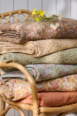 Vikta quilts från Ib Laursen i olika blommiga och mönstrade textilier i varma färger