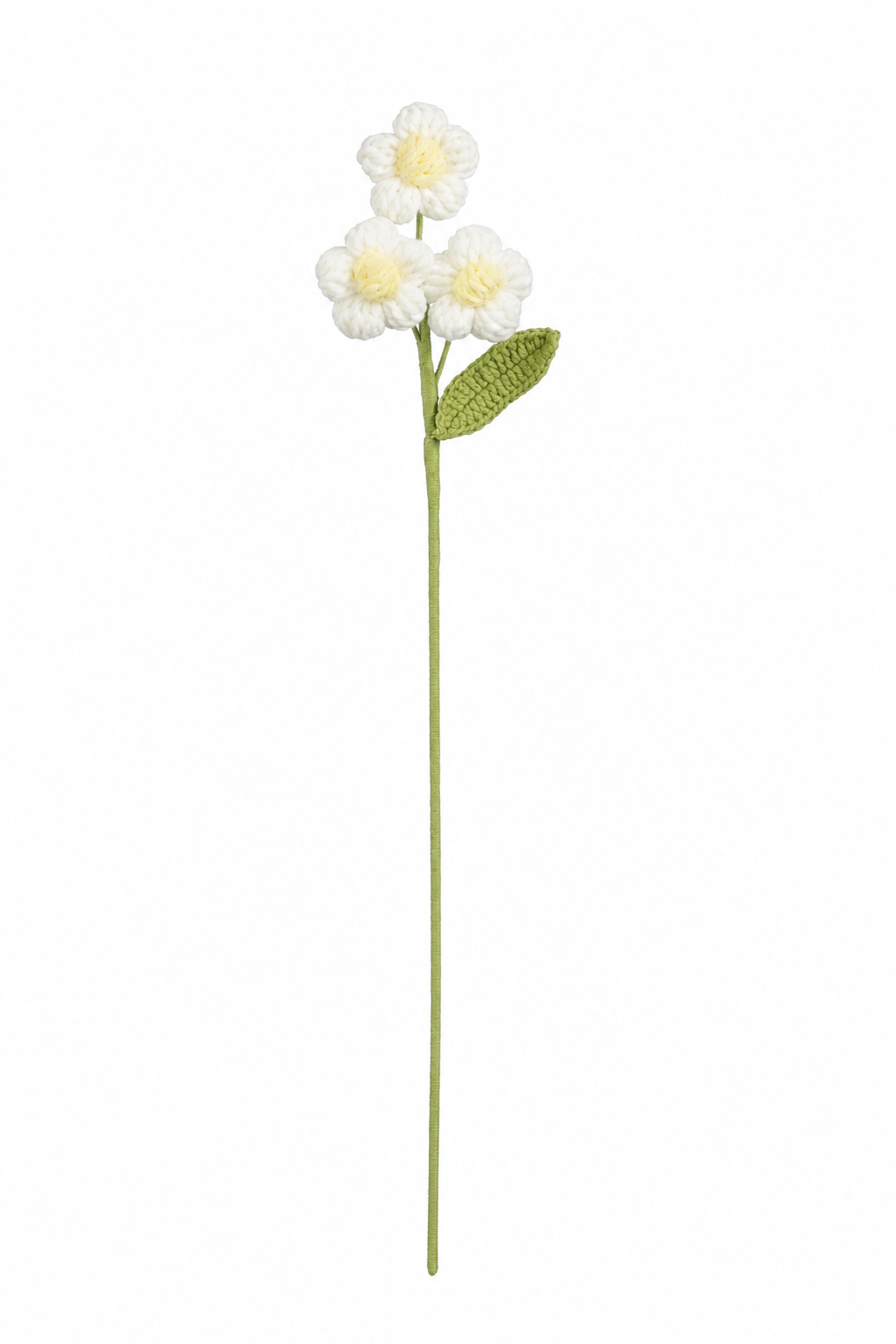 Vit virkad blomstjälk med tre små blommor med gul mitt och grönt blad