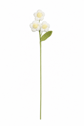 Vit virkad blomstjälk med tre små blommor med gul mitt och grönt blad