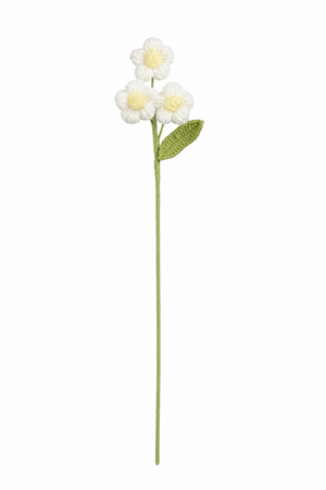 Vit virkad blomstjälk med tre små blommor med gul mitt och grönt blad
