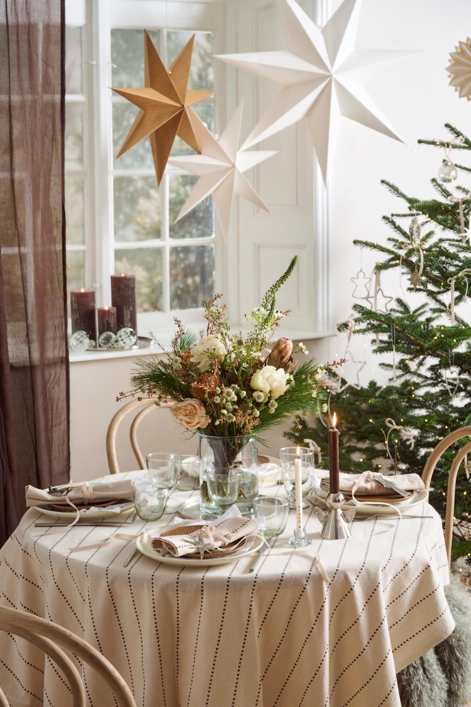 Ljus juldukning i naturfärger med sammetsband, blommor, gran och hängande julstjärnor