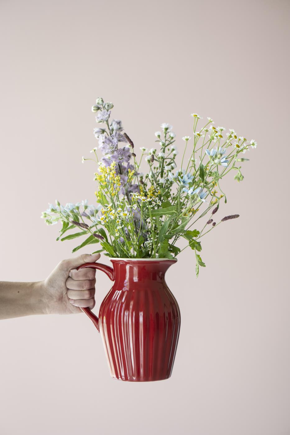 Jordgubbsröd Myntekanna använd som vas med lila och vita sommarblommor