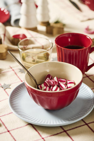 Jordgubbsrött myntmugg på ett mysigt julbord med skål, godis och levande ljus