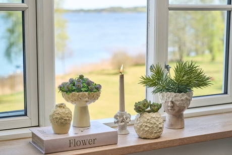 Vas i ljusgul keramik med blommönster pryder en fönsterbräda
