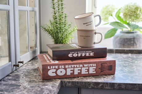 Två bokformade förvaringsboxar med kaffetema och två kaffekoppar ovanpå