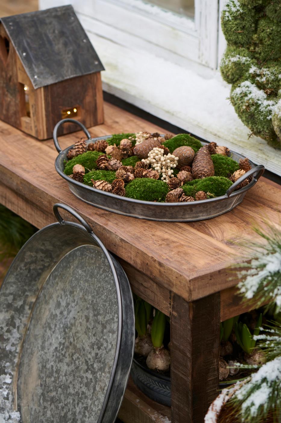 Oval Urban Garden-bricka med mossa, kottar och naturmaterial som vinterdekoration på ett träbord