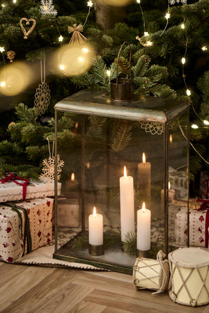 Magnetiska ljusstakar med kronljus i glaslyktor, prydda med grangrenar vid julgranen