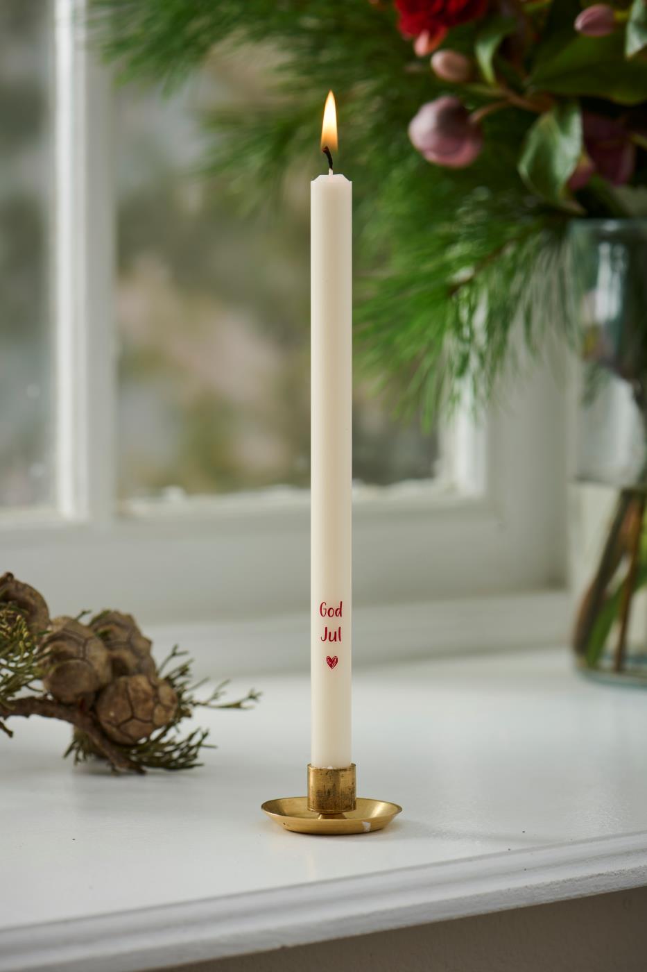 Liten ljusstake i mässing med vitt kronljus, dekorerad med röda julmotiv