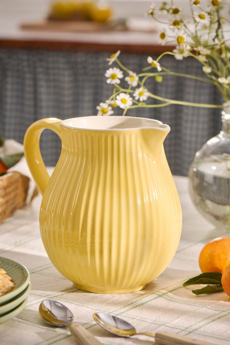 Myntkanna i lemonadgul på ett bord med blommor