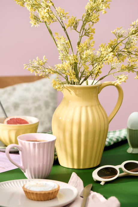 Kanna i lemonadgul från Ib Laursen med gula blommande grenar.