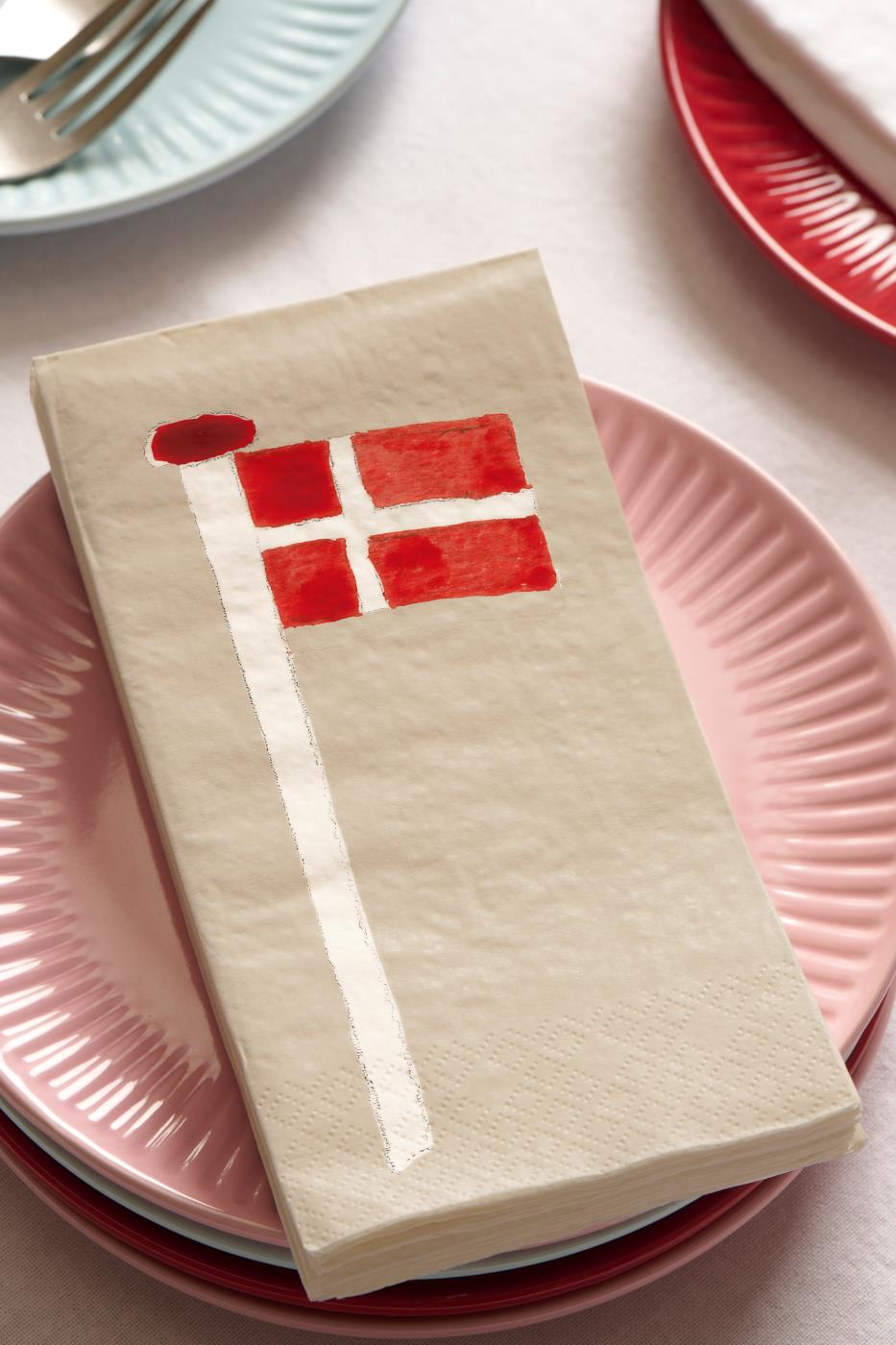 Servietter med Dannebrog på flagstang ligger på en tallerken