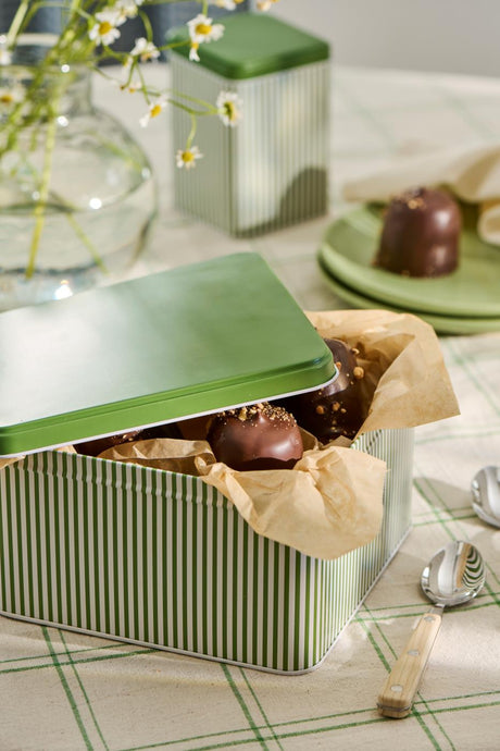 Dåse med grønt låg og grønne og hvide striber fyldt med fyldte chokolader