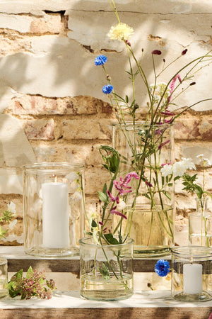 Cylinderglasvaser i klart glas med blomster og stearinlys i